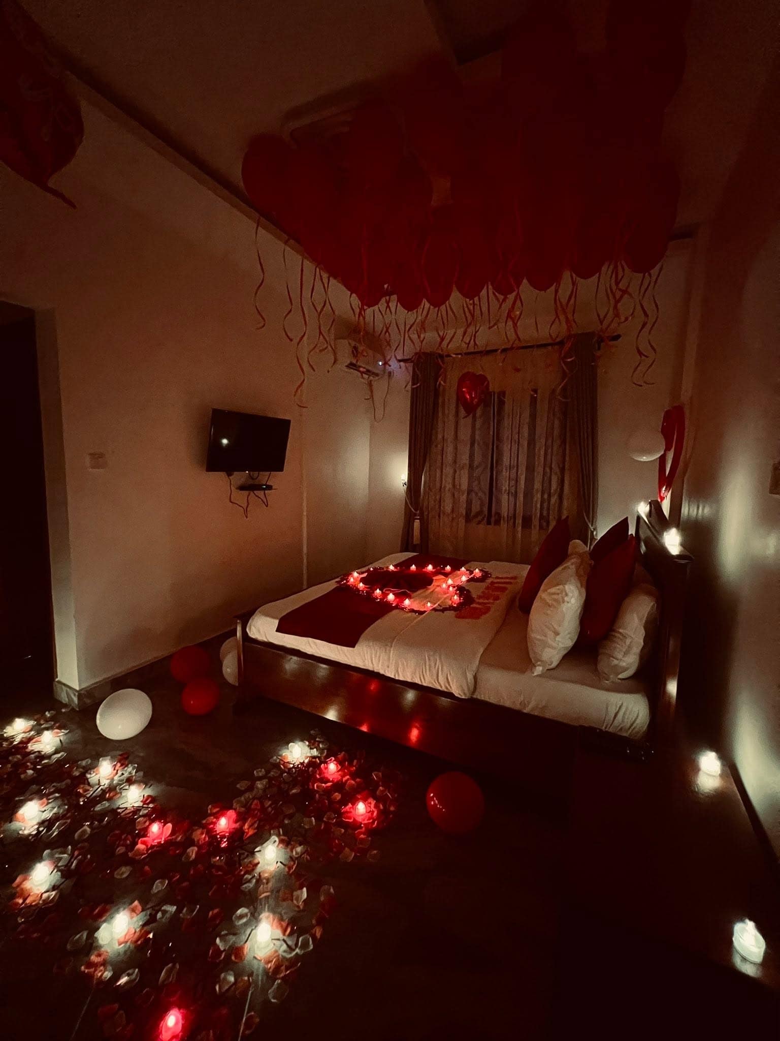 Chambre dressée pour la Saint-Valentin — pétales de rose, bougies et ballons