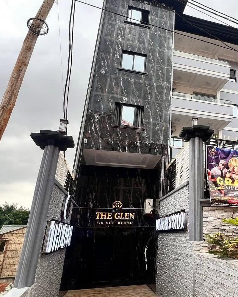 L’entrée du Glen Lounge — tour en marbre noir, enseigne « The Glen · Lounge-Resto » dorée au-dessus de la porte, piliers gris de part et d’autre
