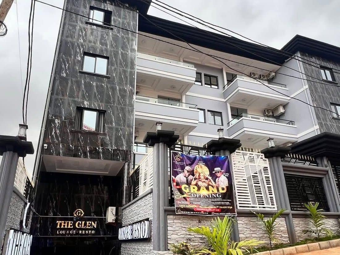 L’immeuble du Glen Lounge en journée — enseigne « The Glen · Lounge-Resto » en marbre noir, trois étages de balcons d’appartements au-dessus