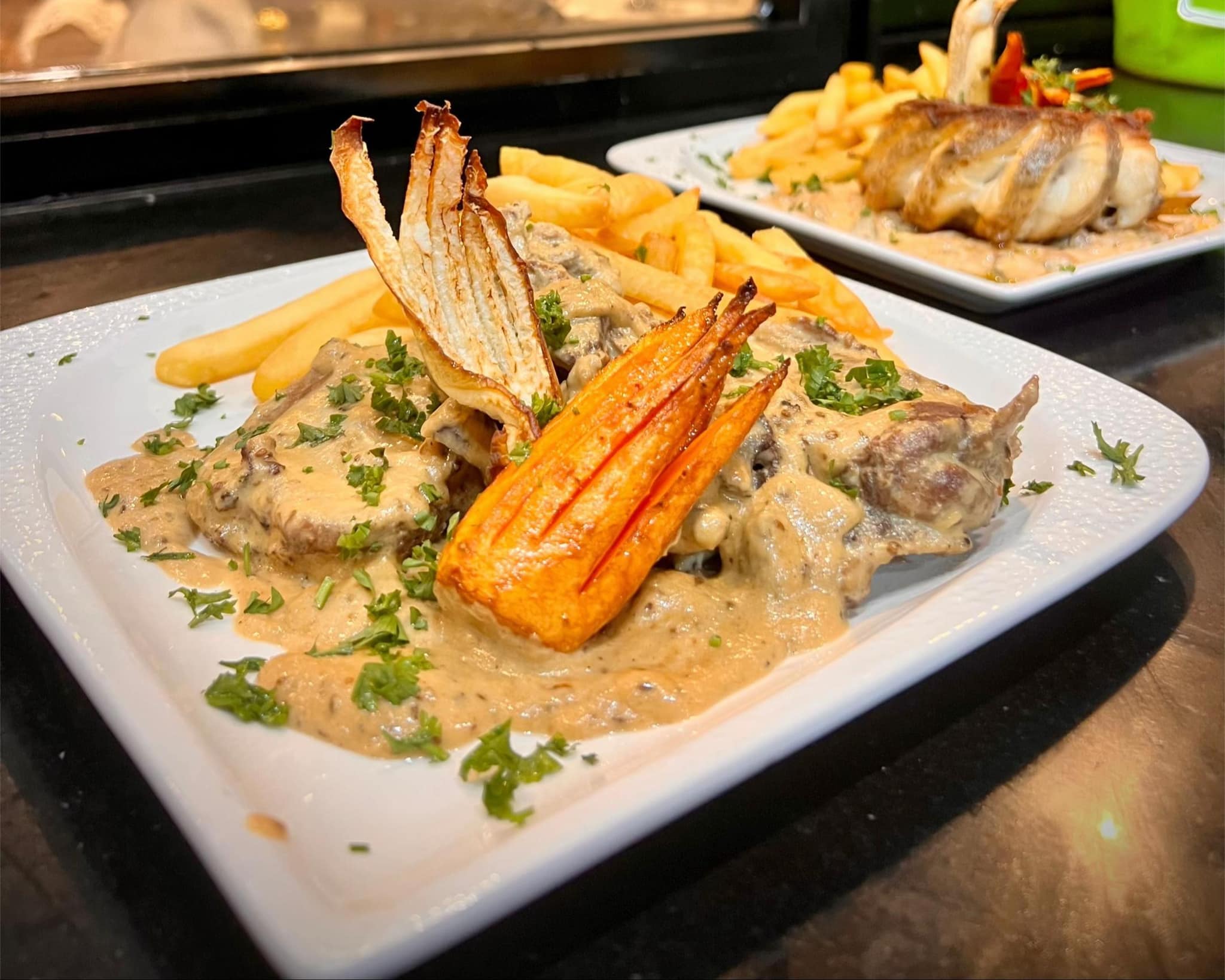 Deux assiettes — viande en sauce crémeuse aux champignons, frites et carottes rôties