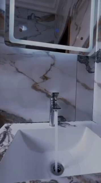 Douche de la chambre A10 — vasque, robinetterie chromée, miroir rétro-éclairé et faïence en marbre veiné