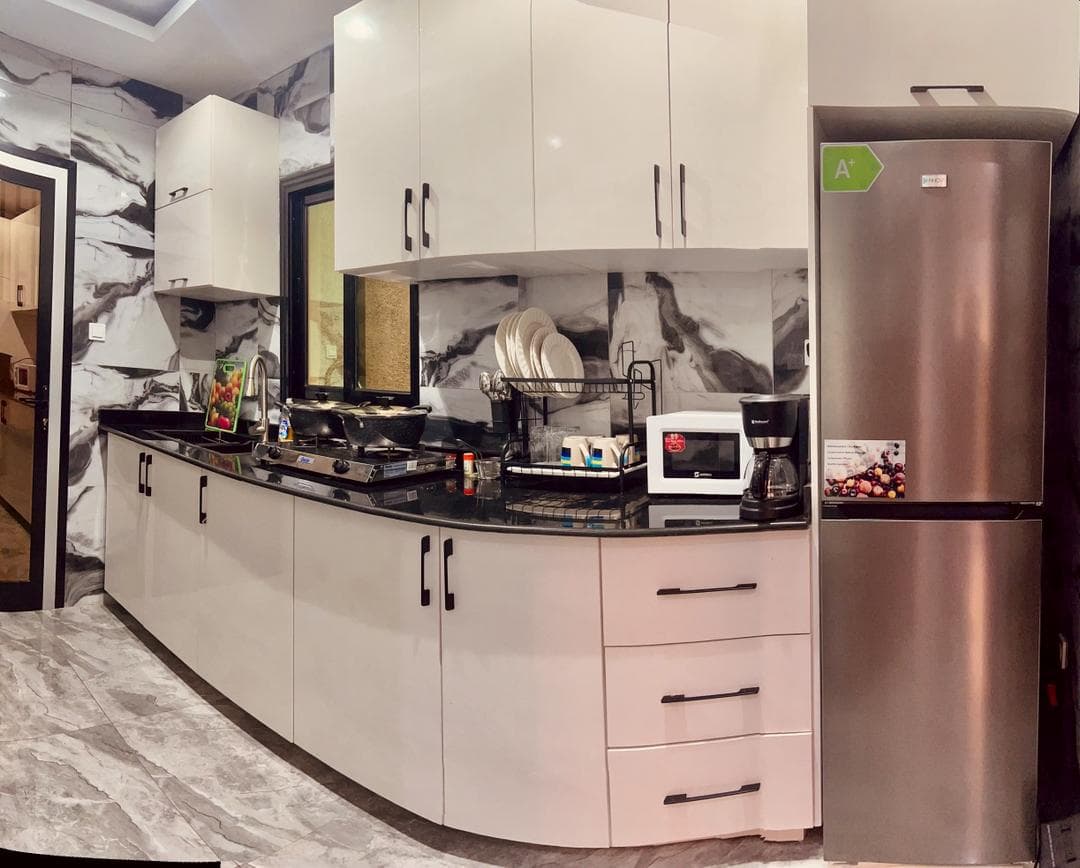 Cuisine équipée du studio SS101 — plan de travail en granit noir, plaque gaz, micro-ondes, cafetière, réfrigérateur et égouttoir garni